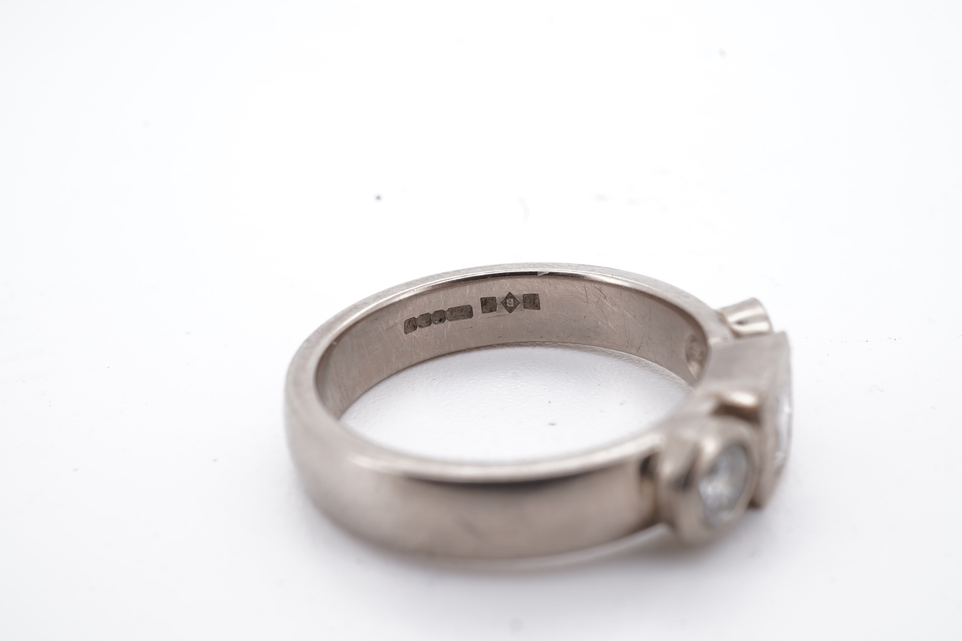 A modern 18ct white gold and three stone diamond ring, set with single square cut diamond and two round cut diamonds, size K, gross weight 5.8 grams.